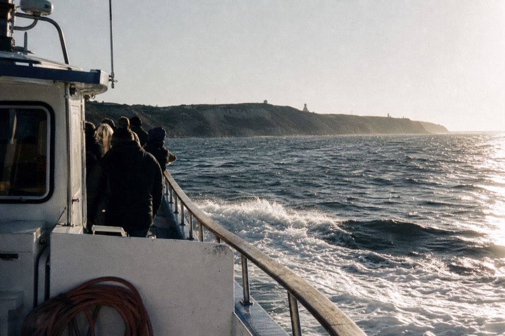 A small whale watching boat cruising past the Point Loma headland, no text, no logos, no people