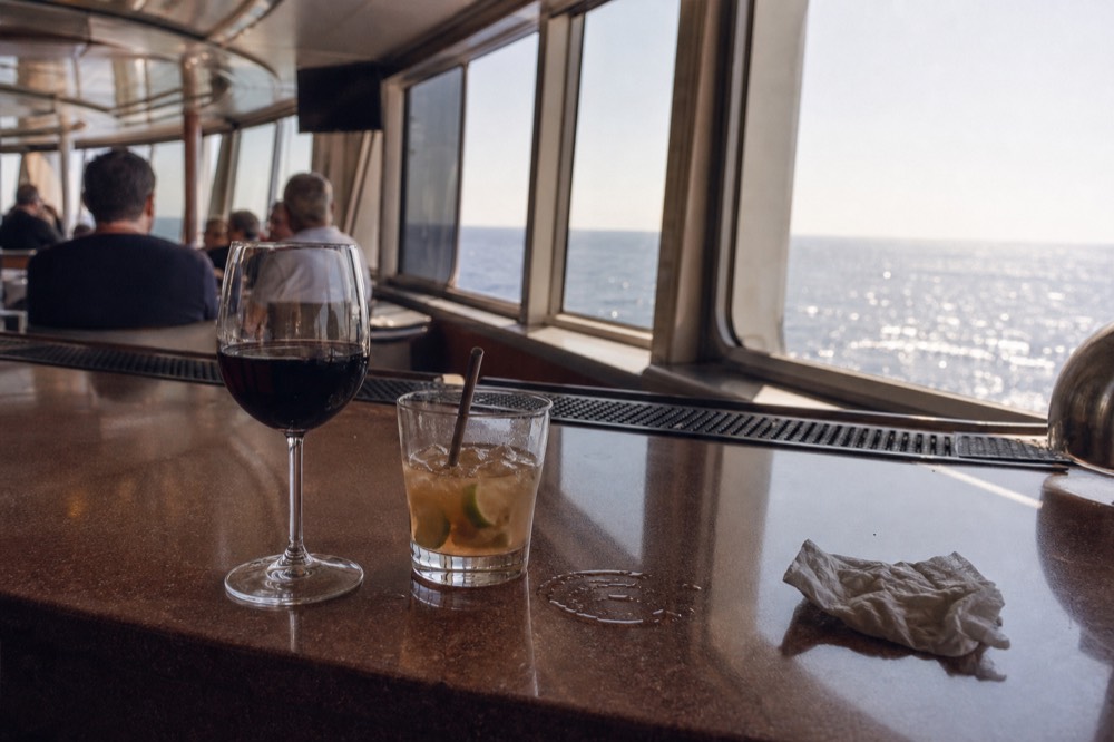 A glass of wine and a cocktail on a cruise ship bar counter, no text, no logos, no people