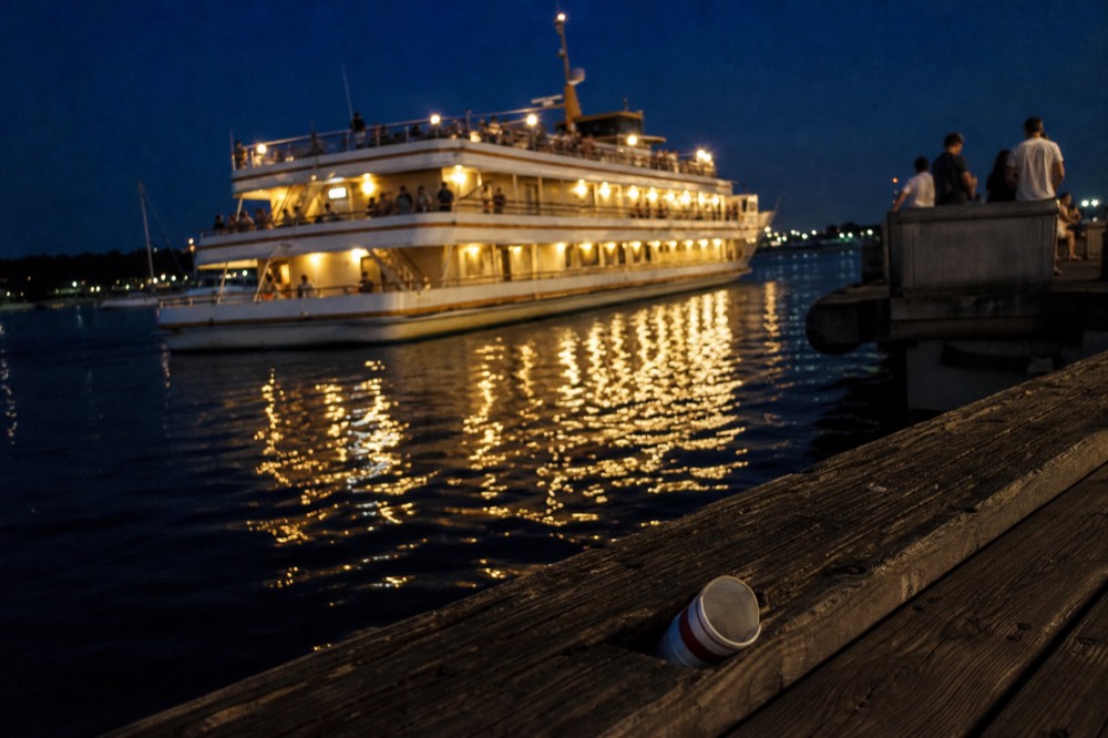 A dinner cruise boat underway on San Diego Bay at golden hour with the Coronado Bridge behind, no text, no logos, no people.