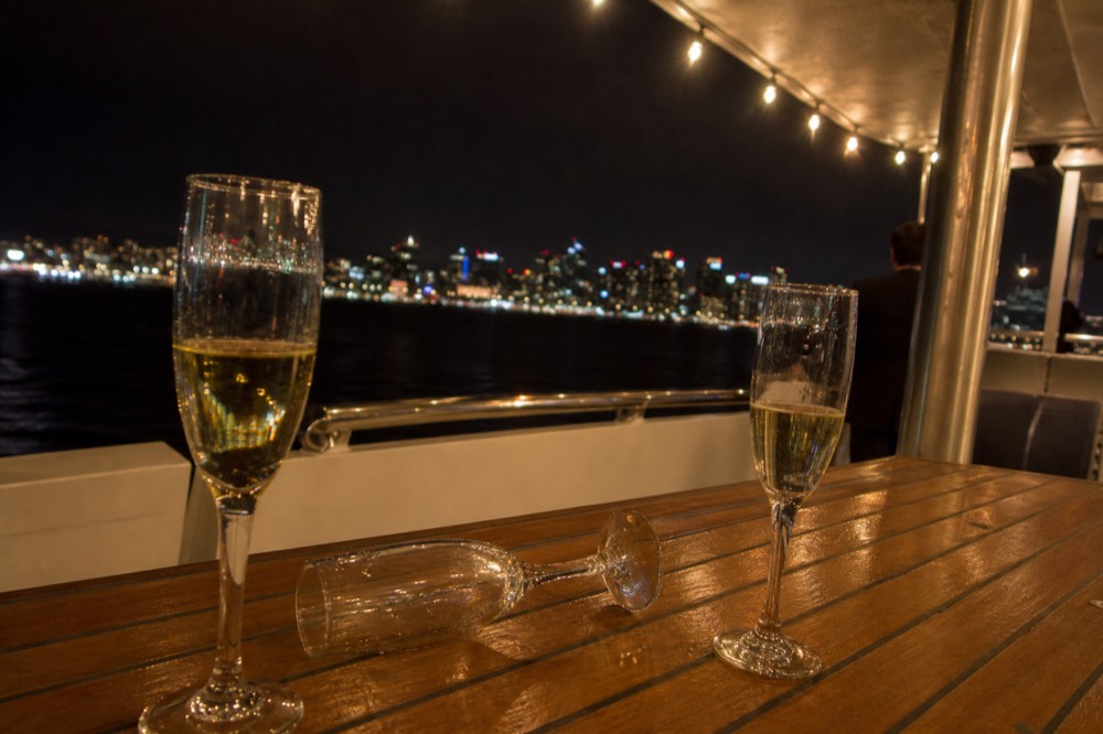 Champagne flutes on a boat deck with San Diego lights in the background, no text, no logos, no people