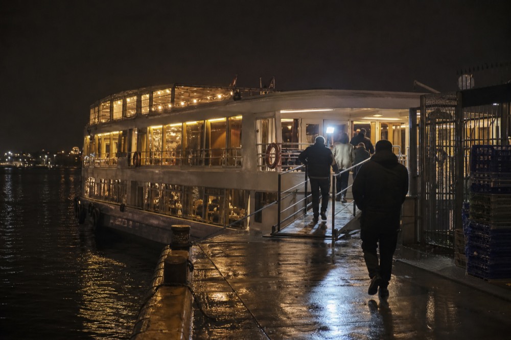 A lit cruise boat docked at a San Diego pier at night, no text, no logos, no people