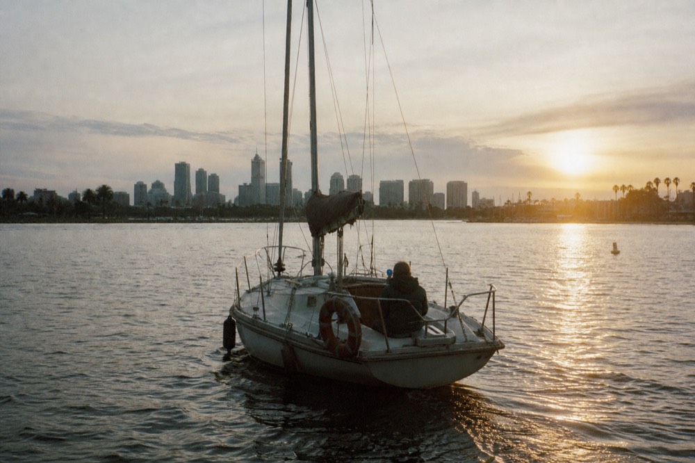 Small sailboat on Mission Bay with the sun low over the water, no text, no logos, no people
