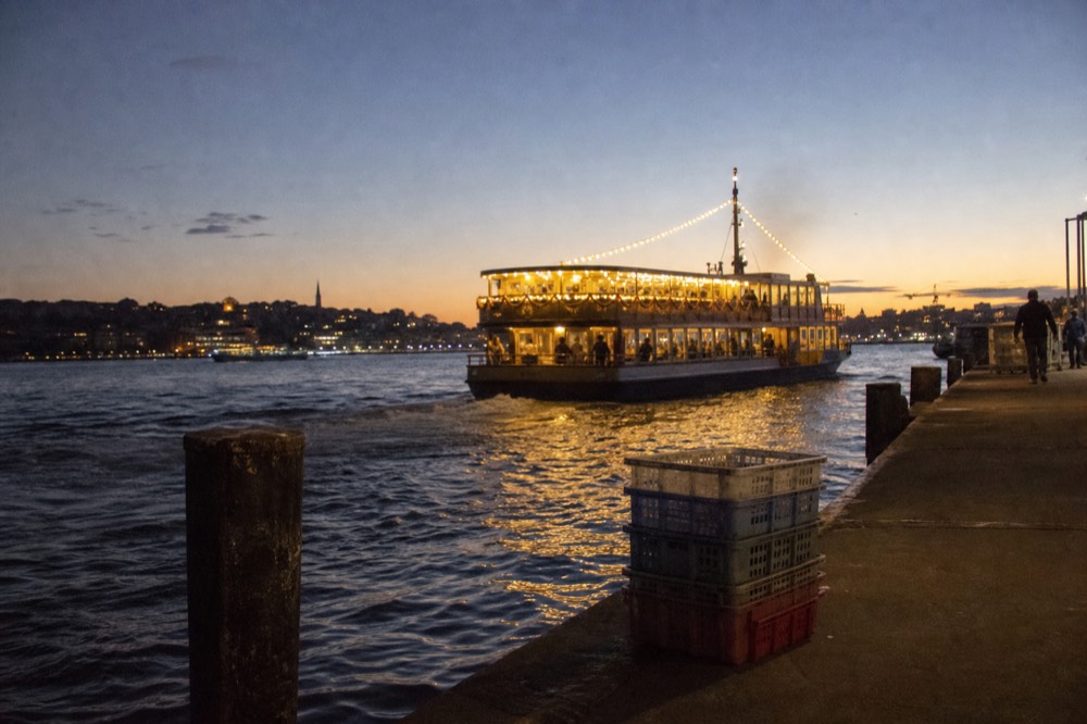 Dinner cruise boat lit up along the San Diego waterfront at dusk, no text, no logos, no people