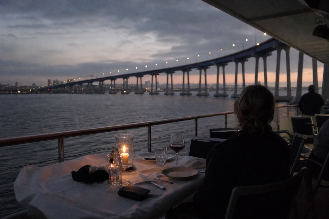 A candlelit dinner table set beside a dark bay at dusk, no text, no logos, no people.