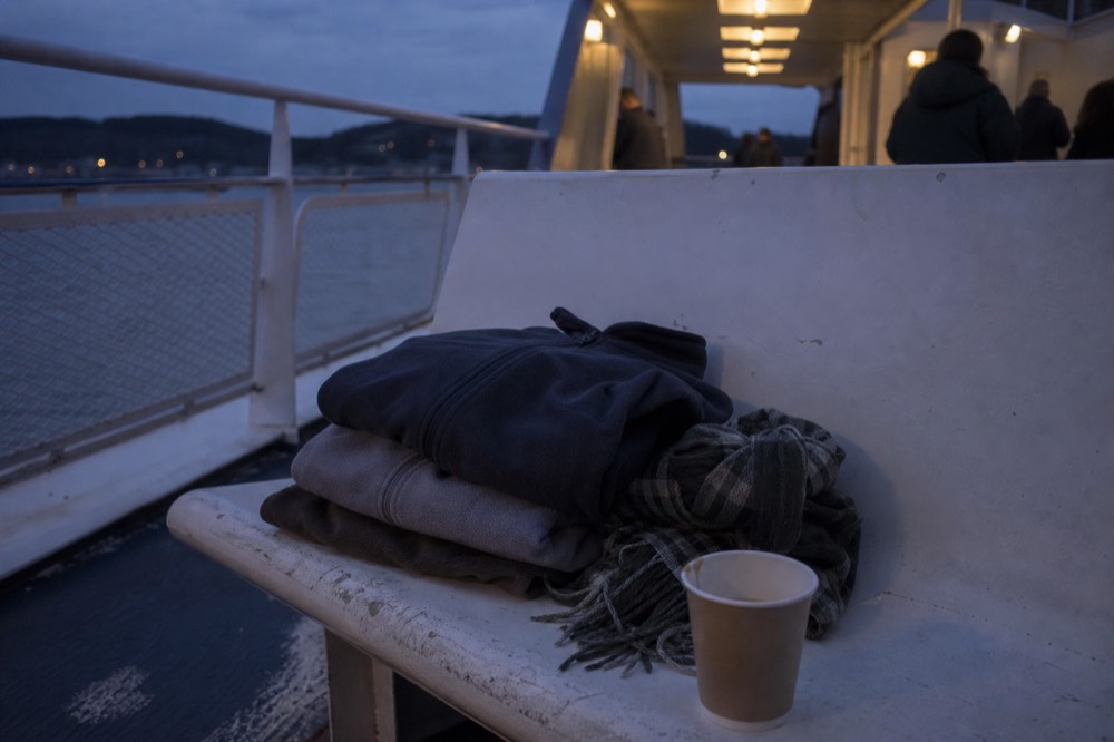 A folded stack of layered clothing and a windbreaker on a boat deck seat, no text, no logos, no people.