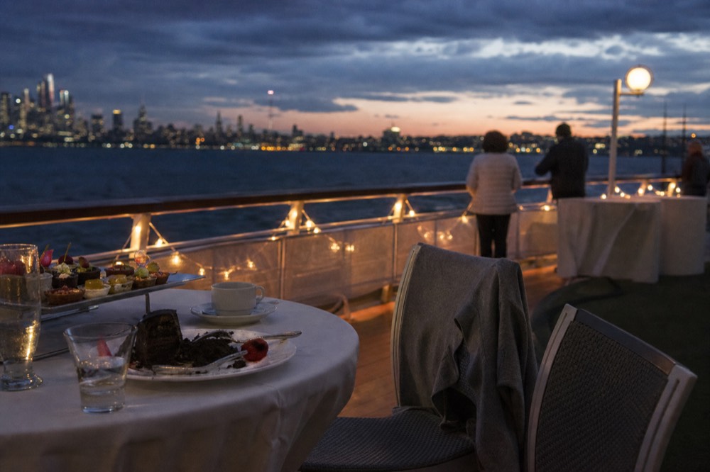 Holiday table setting with desserts on a cruise ship deck at dusk, no text, no logos, no people