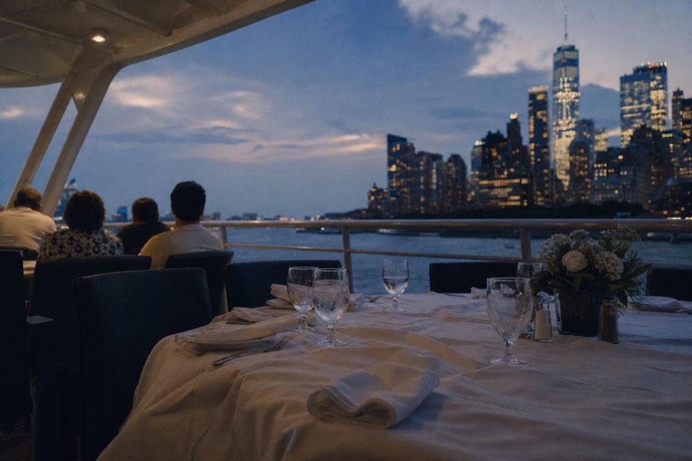 A set dinner table on a boat deck with the San Diego skyline behind it, no text, no logos, no people