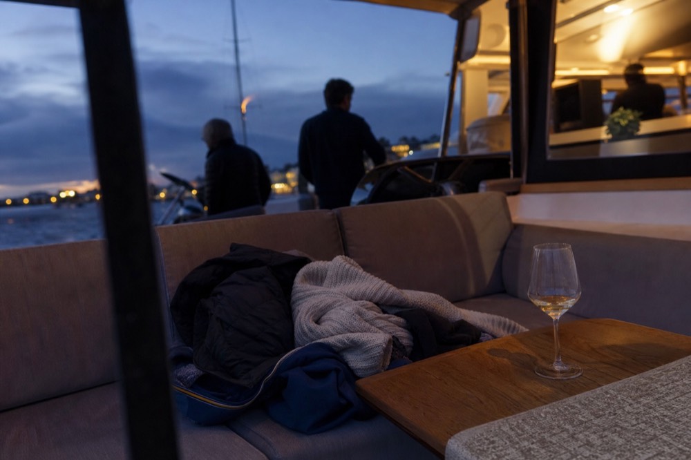 Coats and layers draped over deck seating on an evening boat, no text, no logos, no people
