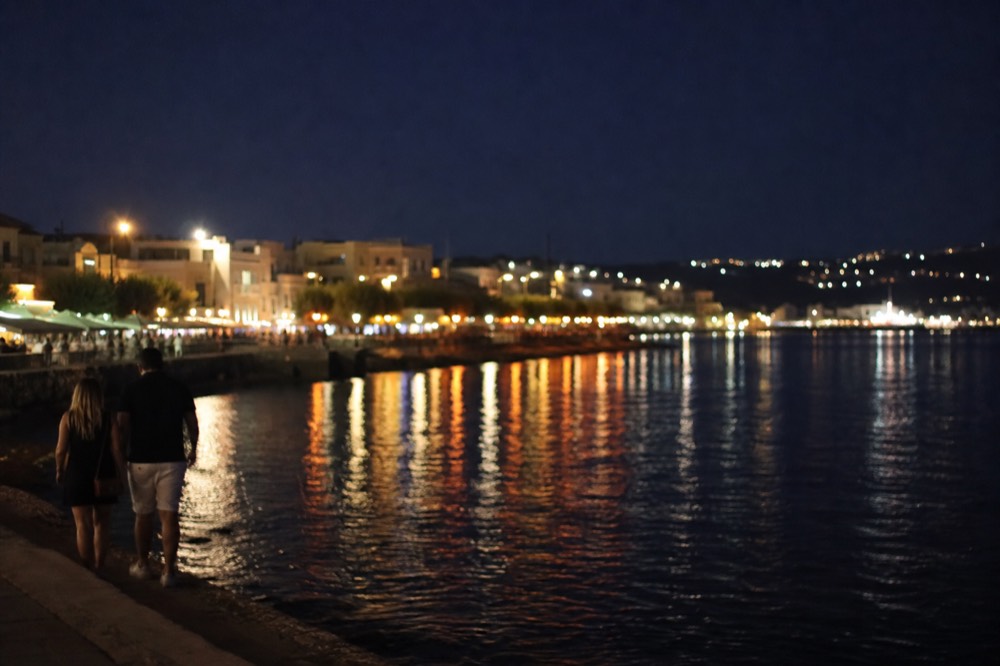 Evening city lights along the waterfront seen across dark bay water, no text, no logos, no people