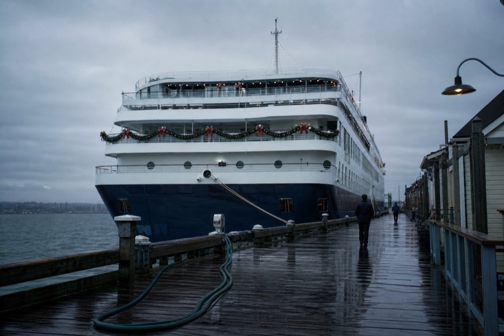 A cruise boat strung with holiday lights moored at a San Diego Bay pier in the evening, no text, no logos, no people