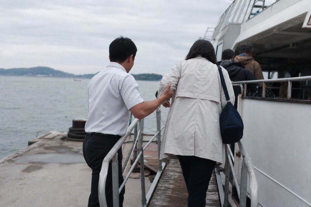 A crew member assisting a passenger along a cruise boat boarding ramp at the pier, no text, no logos, no people