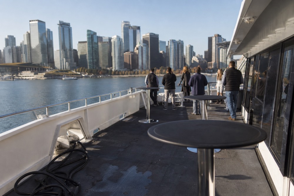 A yacht deck arranged for a private event cruising past the downtown San Diego skyline, no text, no logos, no people