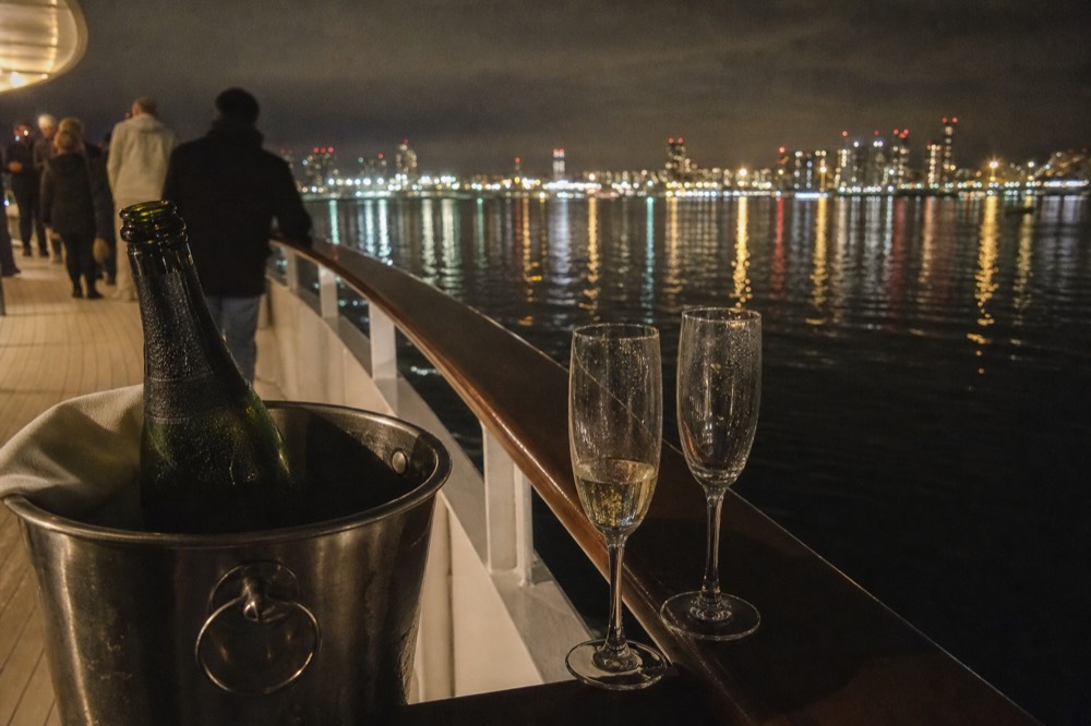 Champagne glasses on a cruise deck at night with city lights reflected on San Diego Bay, no text, no logos, no people