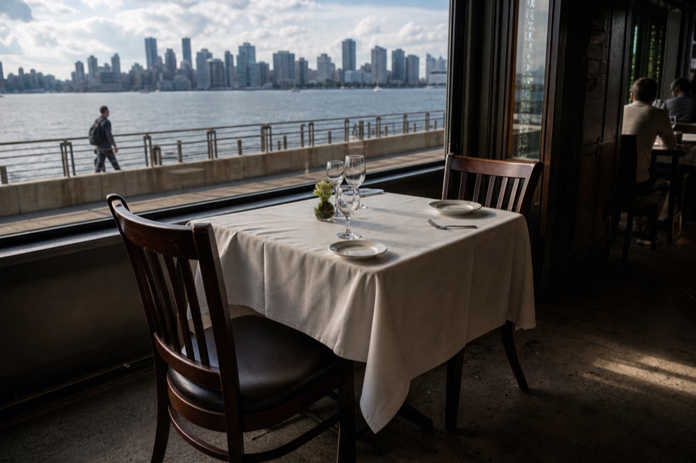 A set dinner table for two beside a large window with the San Diego skyline outside, no text, no logos, no people