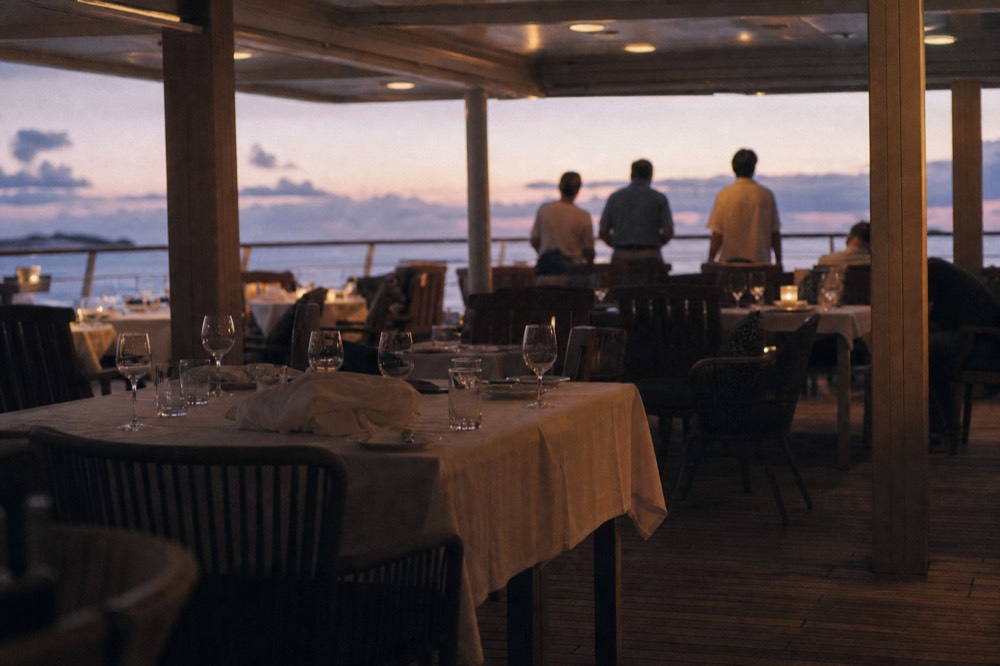 An elegant dining room on a dinner cruise ship with white tablecloths and warm lighting, no text, no logos, no people