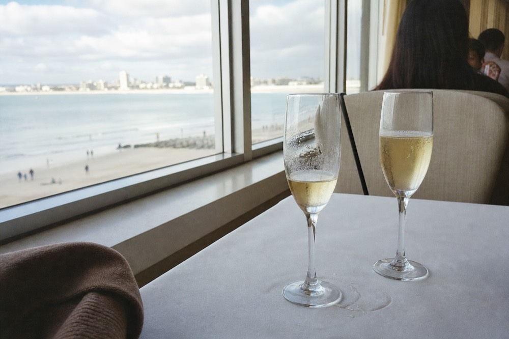Champagne flutes on a cruise ship dining table with bay views through the windows, no text, no logos, no people