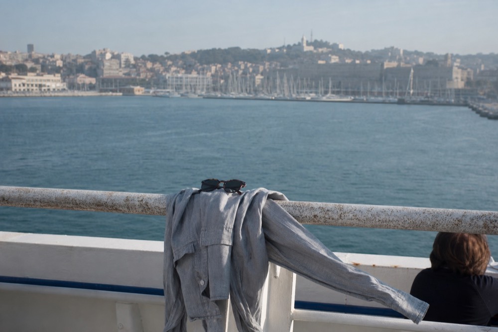 Light jacket and sunglasses on a cruise ship rail with San Diego Bay in the background, no text, no logos, no people