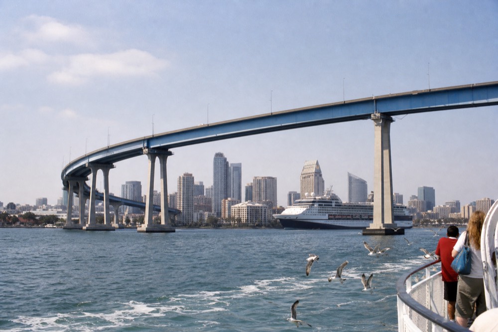 Cruise ship on San Diego Bay with the Coronado Bridge and downtown skyline in midday light, no text, no logos, no people