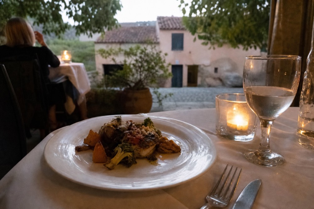 Plated entree with vegetables served on a white plate at a candlelit dinner table, no text, no logos, no people