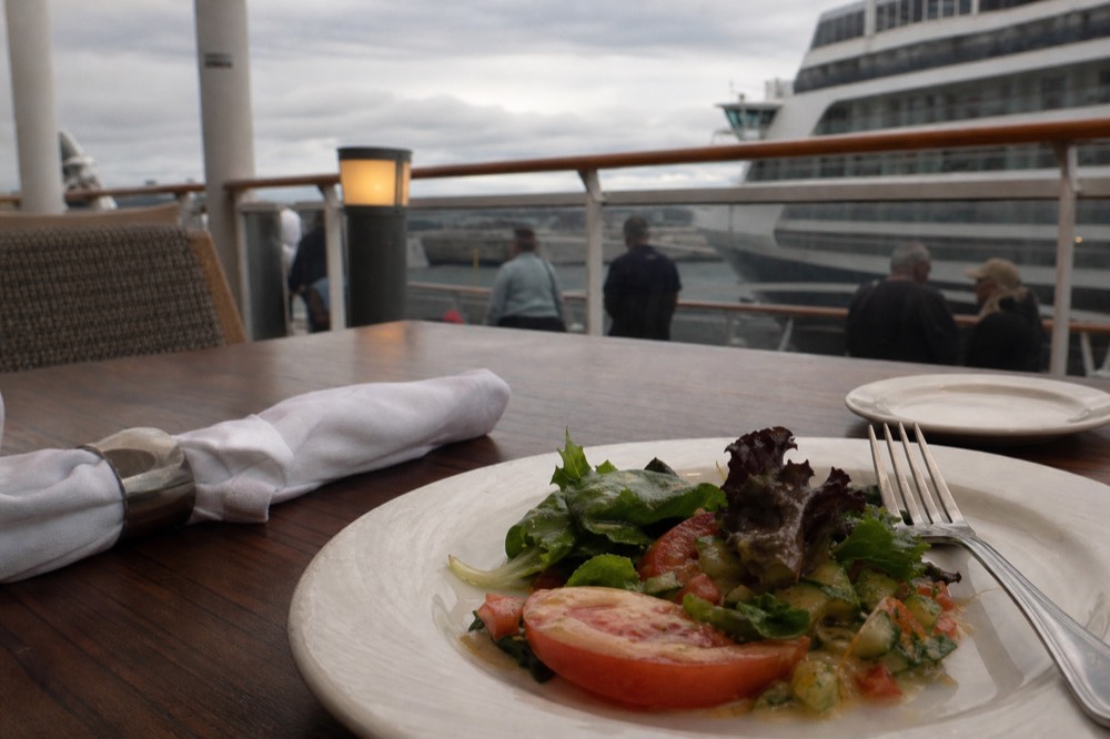 Fresh salad plate with greens, tomatoes, and vinaigrette at a cruise dining table, no text, no logos, no people