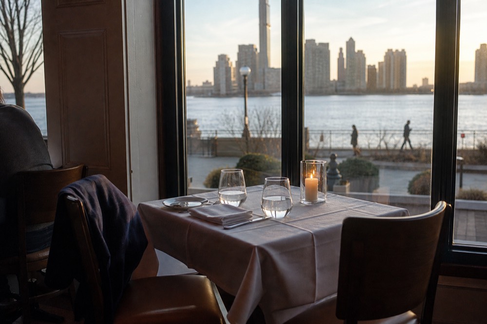 Couple's dinner table set for two beside a window with the downtown skyline outside, no text, no logos, no people