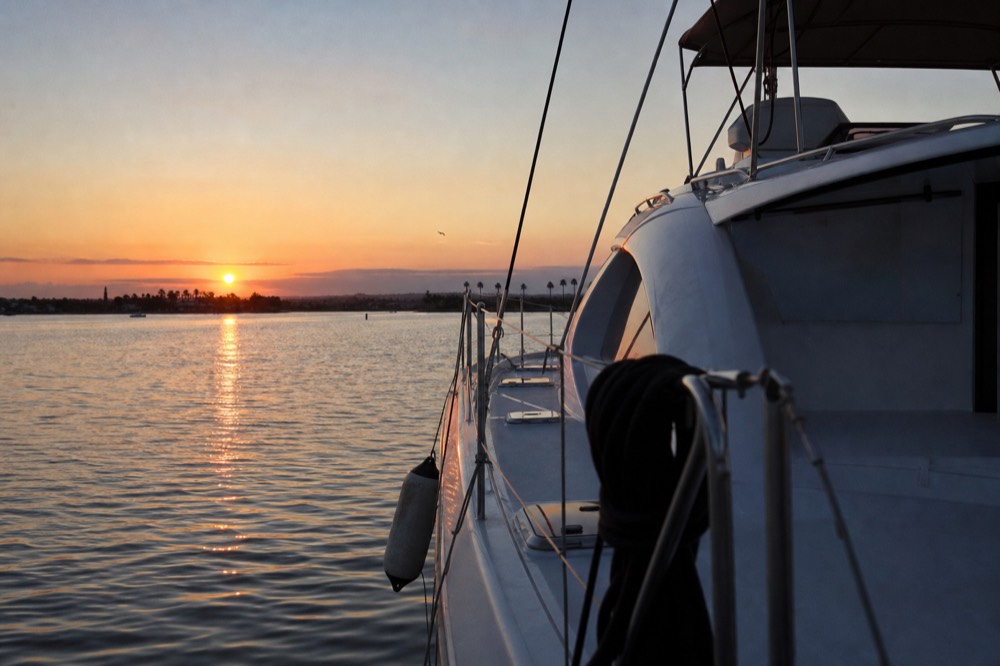 A catamaran anchored in Mission Bay with the sun low over the water, no text, no logos, no people