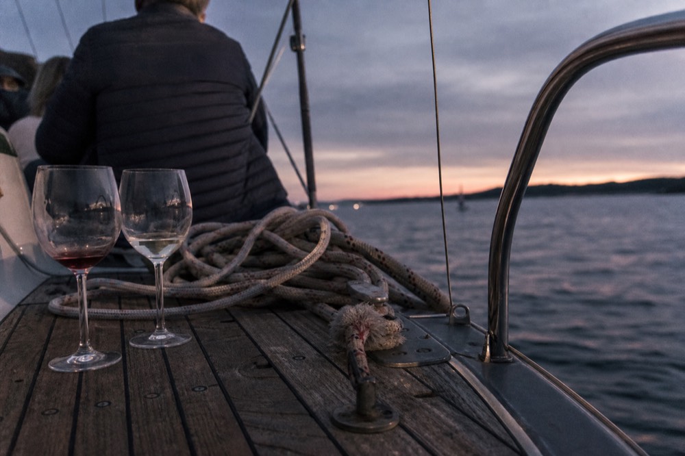 Wine glasses and a sailing rig on a boat deck at dusk, no text, no logos, no people