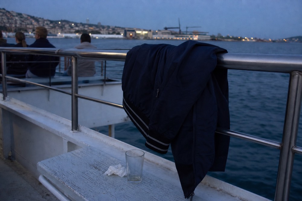 A jacket draped over a rail on a boat deck as evening light fades, no text, no logos, no people