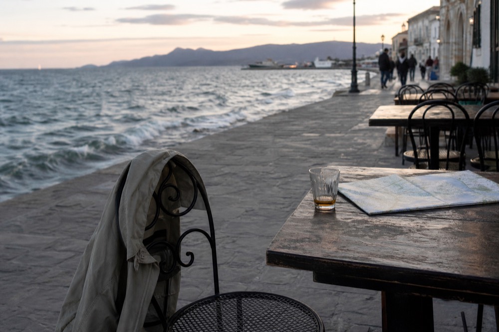 Evening outfit with light jacket draped over a chair facing an open bay view, no text, no logos, no people