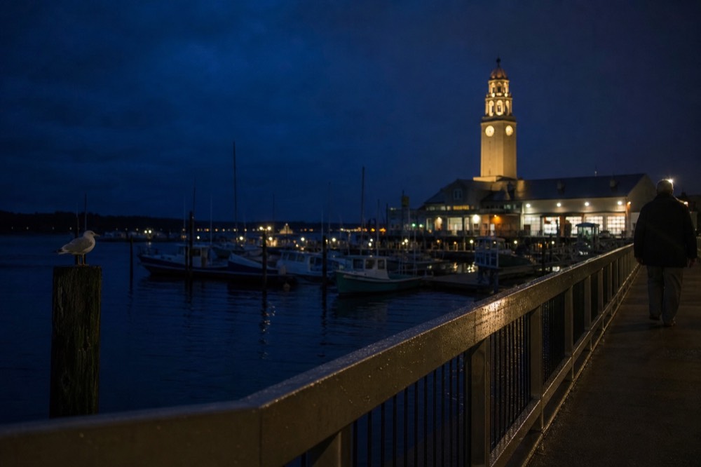 Clock and harbor lights at night on a pier with boats moored nearby, no text, no logos, no people